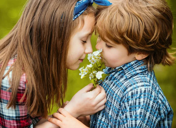 かわいい子供たちがタンポポを吹いている タンポポの花を吹いて牧草地に座っている子供たちは幸せで遊び心があります — ストック写真