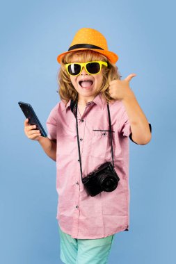 Cute child takes picture with camera and phone. Traveller kid boy chatting on phone. Vacation travel lifestyle. Travel and tourism concept