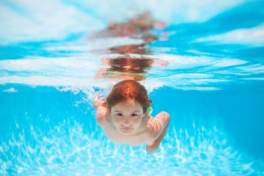 Kid boy swimming underwater on the beach on sea in summer. Blue ocean water. Child boy swimming in sea. Summer kids in water in pool underwater