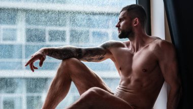 Handsome muscular man in bedroom on window curtains. Young handsome sexy man resting at home. Guy with athletic muscles. Sexy young handsome naked man on bedroom. Seductive gay