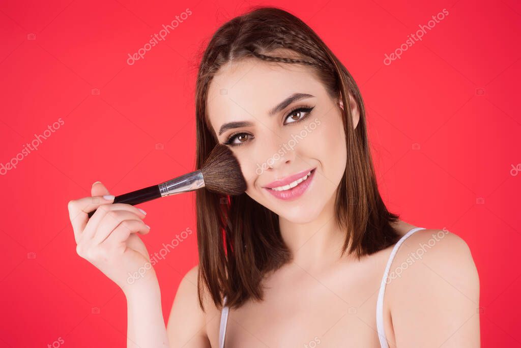 Young woman applies powder on the face using makeup brush. Beautiful