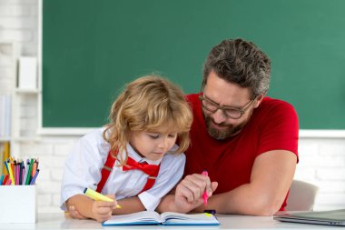Teacher helping child student pupil from elementary school in classroom. Pupil kid student and teacher tutor in classroom at school lesson