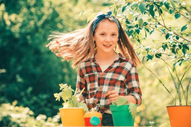 Küçük kız bahçıvanlık yapıyor ve bahar bahçesinde eğleniyor. Ota çiçek eken bir çocuk. Bahar güneşli bir günde bahçede çiçek sulayan tatlı küçük bir kız. Çevre hayatı. Esrarlı küçük kız. Saklı