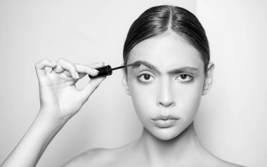 Genç ve güzel bir kadın doğal kaş makyajı yapıyor. Profesyonel çıplak makyajlı ve pürüzsüz sağlıklı ciltli bir kızın portresi. Güzel kız kaş makyajı için jel kullanıyor.