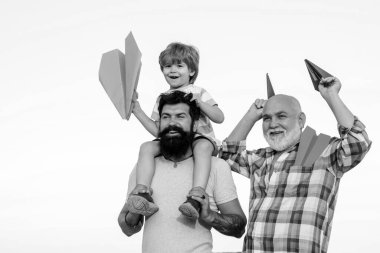 Mutlu gülümseyen çocuk, baba kameraya bakıyor. Üç farklı nesil: büyükbaba ve çocuk birlikte.