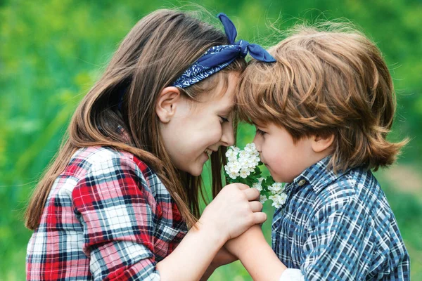 子供たち女の子と男の子吹いてタンポポの花で緑の牧草地屋外 — ストック写真