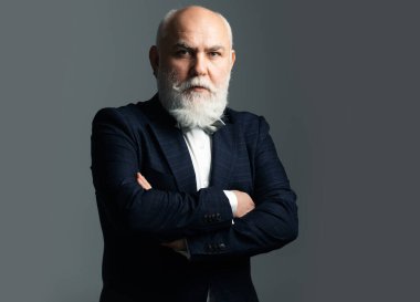 Kıdemli adam. Olgun iş adamı gri kameraya bakıyor.