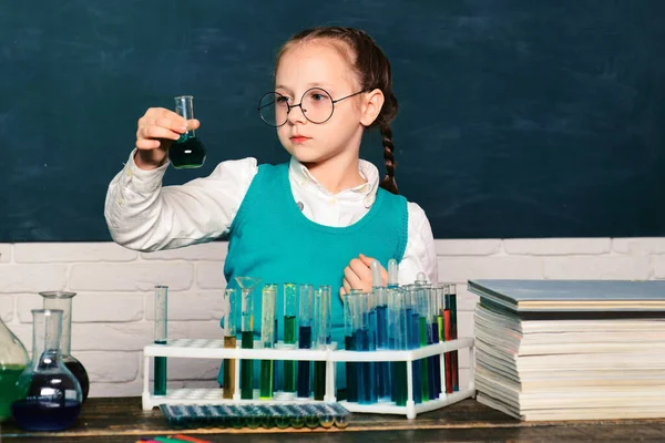 What is taught in chemistry. Chemistry science. Child in the class room with blackboard on background. Child from elementary school