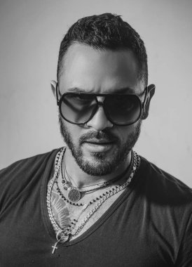 Güneş gözlüklü yakışıklı bir adam. Erkek yüzü. Yakışıklı, erkeksi bir adamın portresi. Gri duvara karşı memnun iş adamının portresi. Güneş gözlüğü. Şehir modası