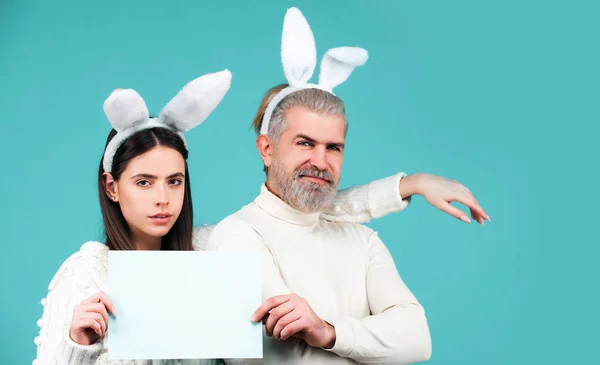 Easter bunny man and woman hold board board for text. Banner with funny bunny couple, copy space