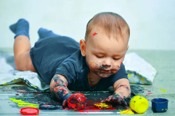 Happy baby child draws with colored paints hands. Happy child draws. Beautiful baby covered in bright paint. Painted in skin hands. Copy space. Early learning. White background