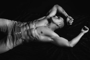 Kaslı erkek gövdesi, çıplak karın kasları. Yatakta yatan adam. Yatak odasındaki seksi adam.