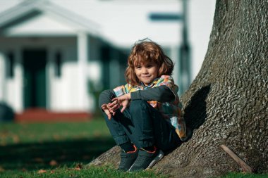 Çocuk dışarıda. Parktaki çocuk. Bahar çocuğu ağacın yanında. Yaz yürüyüşü