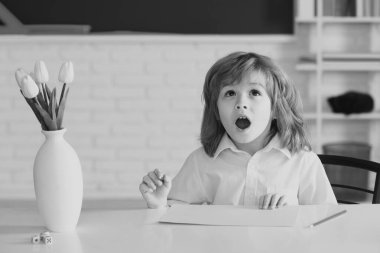 Şaşırmış öğrenci. İlkokul çocuğu eğitimi. İlkokul öğrencisi portresi kapalı alanda çalışıyor. Okuldan sonra. Çocuk okula hazırlanıyor.