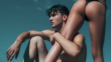 Blue Sky arka planında seksi aşıklar var. Kadınların bacakları ve kalçaları formda. Tutkulu kız arkadaşı olan genç bir adam. Lüks bikinili seksi kız.