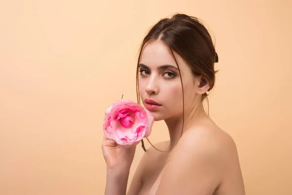 Fashion portrait of young beautiful lady with flowers. Portrait of elegant beautiful woman with naked shoulder hold rose flower, isolated on studio background