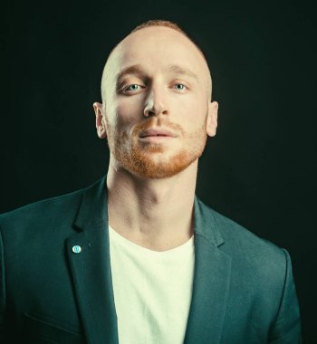 Kendine güvenen bir iş adamı. Genç adamın kameraya baktığı bir stüdyo fotoğrafı. Siyahta yakışıklı adam. Biçim ve eğilim