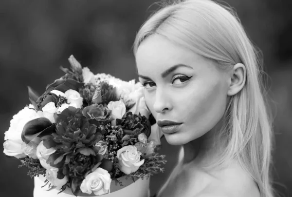 Woman with bouquet flowers, female makeup girl gift. Ideal blonde hair, perfect skin