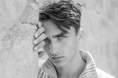 Ciddi bir yüz. Gri arka plandaki yakışıklı genç adam kameraya bakıyor.