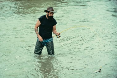 Man fishing on river. Summer vacation. Hobby sport activity. Guy in hat. Fish on hook. Fish normally caught in wild. Pothunter. Nice day for fishing. Senior man fishing