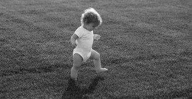 Bahar çocuğu suratlı pankart. Bahar çocuğu suratlı pankart. İlk adım. Yeşil çimlerin üzerinde duran bebek çıplak bacakları. Sağlıklı bir çocuk. Yeşil çim arka plandaki çocuklar