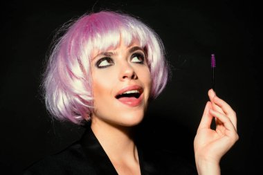 Modellik yapan kaşlar, güzel yüzlü büyüleyici bir bayan, sağlıklı ve temiz bir cilt, elinde fırça ve kaşlarını boyuyor. Siyah stüdyo arka planında izole edilmiş kadın portresi