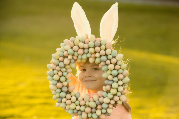 Easter bunny kids. Child boy in bunny Easter ears painting eggs. Funny kids face closeup