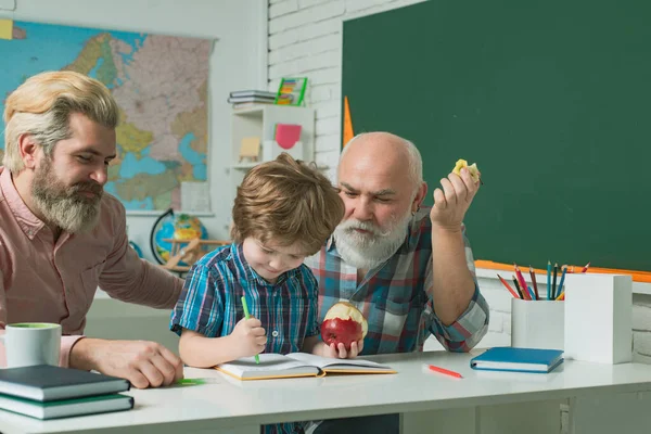 Grandfather father and son learning to write and read, men in different ages ready to study. Happy family in class at school. Three men generation. Senior teacher