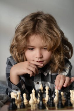 Chess game with children at home. Little kid play chess. Thinking child. Chess game for kids. Intelligent, smart and clever school boy