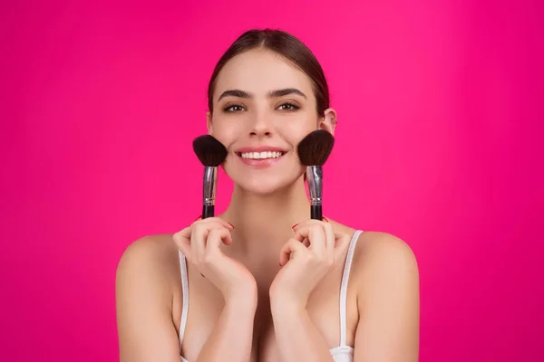 Beauty woman with makeup brushes. Make up for woman. Girl with makeup brushes near face. Cosmetic brush. Facial Makeup. Female model applying blush powder foundation tone