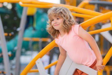 Cute kid having fun at playground. Happy kid having fun on playground. Kid climbing on playground