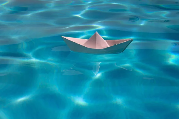 Sailing yacht concept, paper ship with sailing boat. Paper boat on the sea background. Origami paper boat sailing on water causing waves and ripples