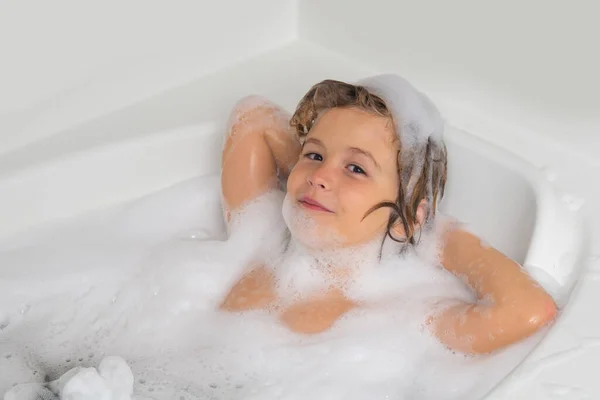 Kid bathing in a bath with foam. Funny kid face bathed in the bath