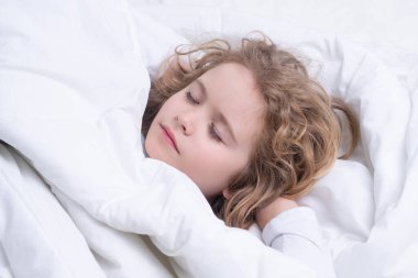 Little kid sleeps on bed, napping. Cute child sleeping. Comfortable bed, soft pillow orthopedic mattress
