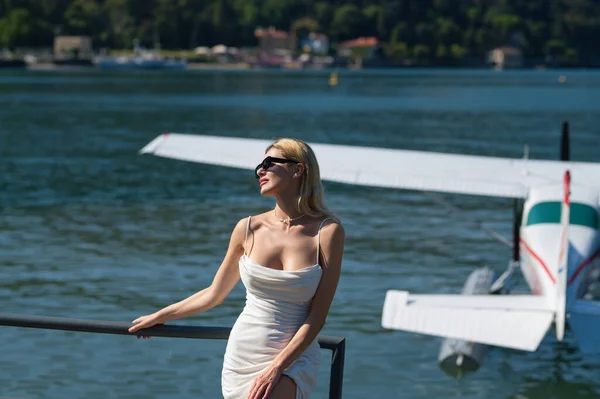 Beautiful model walks away from her private jet on holiday. Business woman near private jet. Luxury travel in Como lake Italy. Charter jet airplane. Sensual woman on the street near jet plane