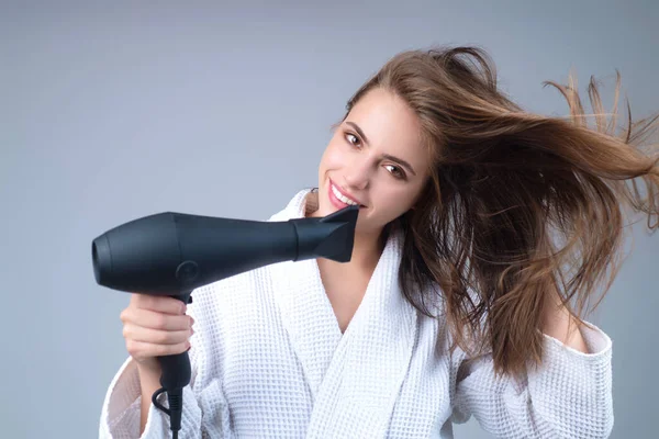 Woman with hair dryer on studio background. Girl hold hairdryer. Young woman drying hairs with hair dry machine. Beauty girl using dries hairs with hair dryer. Beauti model with holding blow dryer