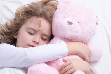 Sleep, sleeping concept. Little boy sleeping with a toy teddy bear in bed. Cute kid sleeping well alone in bed under blanket