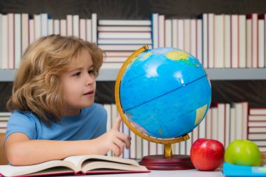 İlkokulun kütüphanesinde kürene bakan sevimli bir öğrenci. Okul çocuğu. İlkokuldan bir çocuk. Öğrenci, git çalış. Zeki okul çocuğu öğreniyor. Çocuklar öğrenim, bilgi ve eğitim