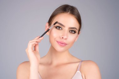 Eyebrow makeup. Beauty model shaping brows with brow pencil closeup. Womans eyebrows with eyebrow brush. Natural make up. Modeling brows. Comb eyebrows