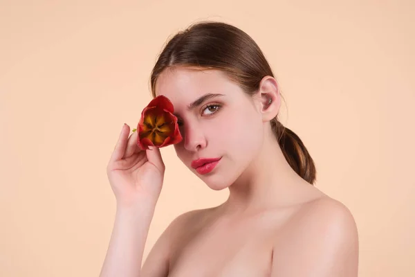 Tenderness and beauty. Youth and skin care concept. Beauty and flower. Sensual girl with tulip near face. Beautiful sensual woman hold tulip, studio portrait on beige background