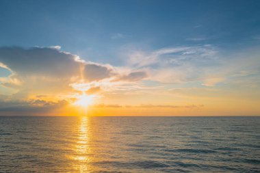 Gün batımı deniz manzarası. Sakin dalgalarla renkli sahil gündoğumu. Doğa deniz göğü. Mavi gökyüzüne ve denize karşı farklı renkte bulutlarla gün doğumu. Okyanus ve gökyüzü arkaplanı, deniz manzarası