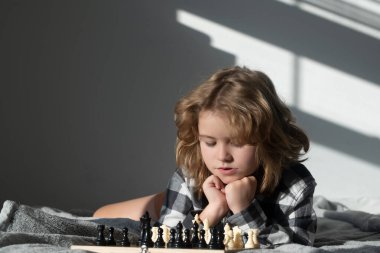 Child playing chess at home. Kid playing chess. Clever child thinking about chess. Kids early development