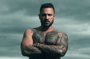 Yakışıklı bir adamın portresi. Güçlü kaslı erkek vücudu, kaslı adam. Dramatik gökyüzünde açık hava erkek portresi