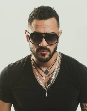 Erkek yüzü. Yakışıklı, erkeksi bir adamın portresi. Gri duvara karşı memnun iş adamının portresi. Güneş gözlüğü. Şehir modası