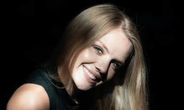 Çekici ve şehvetli görünen güzel kadın modelinin portresi. Siyaha izole edilmiş dramatik stüdyo ışığı olan güzel bir yüz. Sarışın kız, yüzünü kapat.