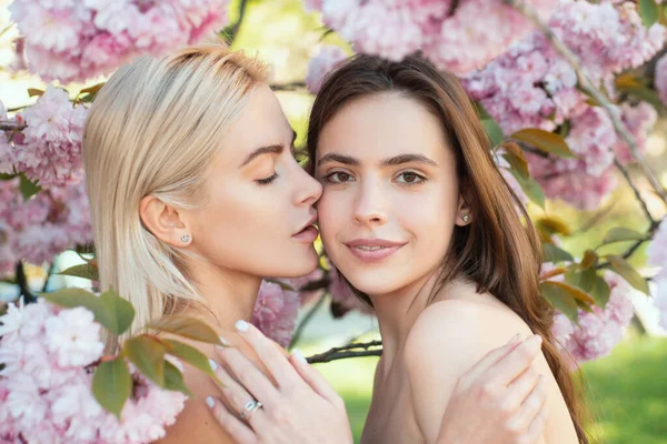 两个美丽的春天女孩的画像 两个年轻的女人在樱花中放松 同性恋夫妇亲吻 性感的触摸和亲吻 女朋友们 — 图库照片