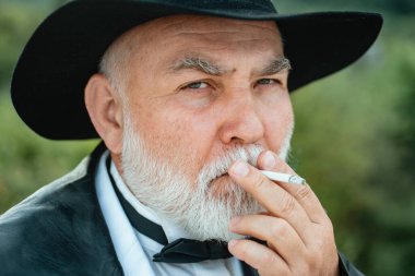 Sigara içen yaşlı adam. Çekici, yaşlı, olgun bir adam. Son sınıf modasının yüzü. Yakın çekim.