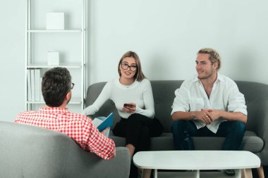 Sosyal Hizmetler psikoloğu genç bir çiftle konuşuyor. Depresyon terapisi, aile terapisi.