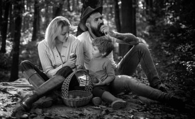 Happy family with kid boy relaxing while hiking in forest. Mother father and small son picnic. Picnic in nature. Country style family. Meaning of happy family. United with nature. Family day concept.