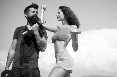 Çekici genç çift boş vakitlerinde fitness egzersizleri yapıyor. Güzel esmer kadın ve sakallı yakışıklı adam mavi gökyüzü arka planında spor fitness aktiviteleri yapıyorlar.